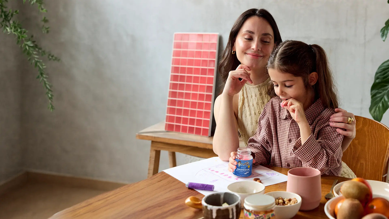 Mutter und Tochter machen zusammen Hausaufgaben. Tochter nimmt Mium Lab Magnesium Vitamingummis
